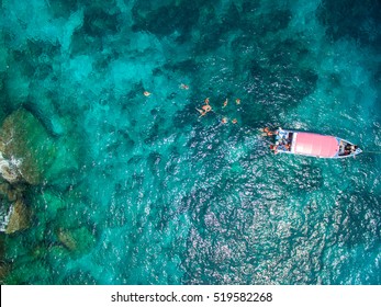 Aerial view of turquoise clear water and speedboat above coral reef. Thailand. Top view of snorkeling people.