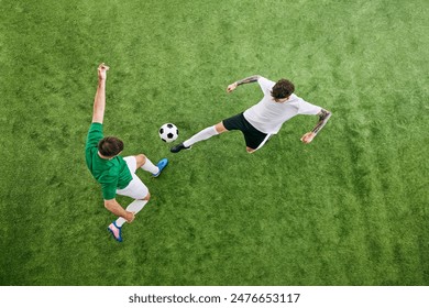 Aerial view. Two football athletes, one in white swings his leg, and other in green braces for play on lush playground. Concept of professional sport, championship, final match, movement. Ad - Powered by Shutterstock