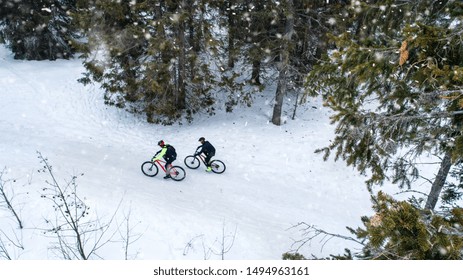 Aerial view of two mountain bikers riding on road in forest outdoors in winter. - Powered by Shutterstock