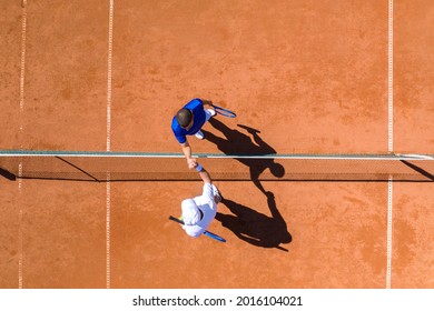 Aerial view of two tennis players greeting each other over the net after finishing the game