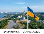 Aerial view of the Ukrainian flag waving in the wind against the city of Kyiv, Ukraine near the famous statue of Motherland.