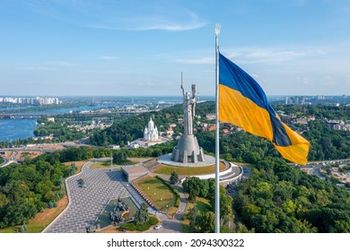 Aerial view of the Ukrainian flag waving in the wind against the city of Kyiv, Ukraine near the famous statue of Motherland. - Shutterstock ID 2094300322