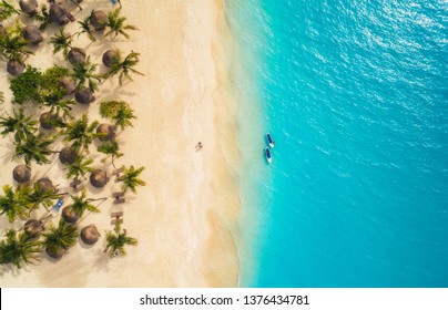 Aerial View Of Umbrellas, Palms On The Sandy Beach And Kayaks In The Sea At Sunset. Summer Holiday In Zanzibar, Africa. Tropical Landscape With Palm Trees, Parasols, Boat, Sand, Blue Water. Top View