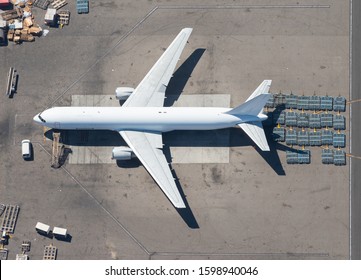 Aerial View Of Unidentifiable Big Aircraft For Freight Transport With Cargo Pallets Around. Freighter White Aircraft Seen From Above. Cargo Transportation Logistics.