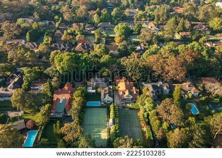 Aerial view of upmarket houses with private gardens, pools, and tennis courts on Sydney's leafy North Shore.