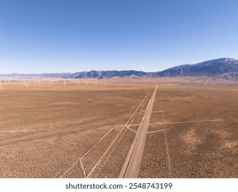 Aerial view of U.S. route 50, the loneliest road in the USA, and of a windmill park in interior Nevada, high desert and snow covered mountains. Clear blue sky. - Powered by Shutterstock