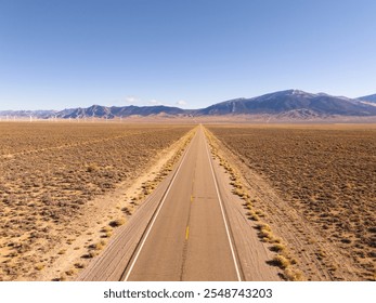 Aerial view of U.S. route 50, the loneliest road in the USA, and of a windmill park in interior Nevada, high desert and snow covered mountains. Clear blue sky. - Powered by Shutterstock