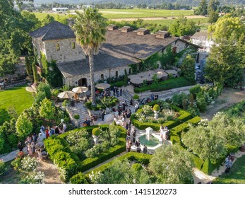 Aerial View Of V. Sattui Winery And Retail Store, St. Helena, Napa Valley, California, USA. People Enjoying Drink And Wedding Event In The Green Garden Surrounded By Vineyard 05/18/2019. 