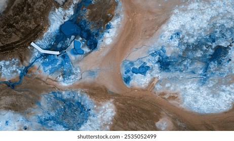 Aerial view of a vibrant geothermal sulfuric field in Iceland, showcasing vivid blue and brown mineral deposits, contrasting the natural textures of the earth. A striking alien landscape. - Powered by Shutterstock