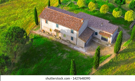 Aerial View Of A Villa At Sunset. The Country House Has A Large Garden With Trees And Plants And Is Surrounded By Nature In The Hills Of Tuscany, Italy. 