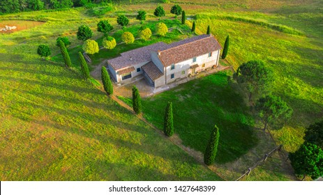 Aerial View Of A Villa At Sunset. The Country House Has A Large Garden With Trees And Plants And Is Surrounded By Nature In The Hills Of Tuscany, Italy. 