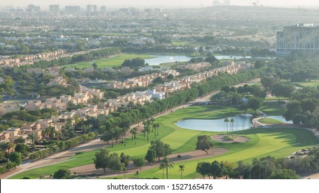 Aerial view to villas and houses with Golf course with green lawn and lakes timelapse. Traffic on streets. Warm evening light