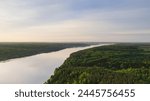 Aerial view of the Volga River, flowing surrounded by a spring green forest and colorful sunrise 