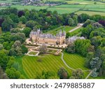 An aerial view of Waddesdon Manor atop a hill surrounded by lush green fields in Buckinghamshire.