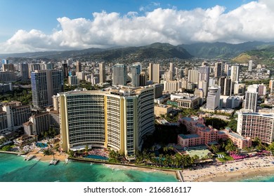 Aerial view of Waikiki Beach tall buildings by the beach in Honolulu, Hawaii. Blue sky with clouds above the mountains - Shutterstock ID 2166816117