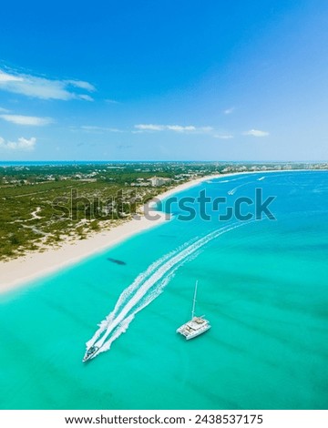 aerial view of wake boat and catamaran sailing on award winning grace bay, providenciales with island and long stretch of white sand beach in sight
