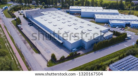 Aerial view of warehouse storages or industrial factory or logistics center from above. Top view of industrial buildings and trucks 