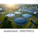 Aerial view of wastewater treatment plant at sunrise, ideal for illustrating sustainable water management, environmental engineering, and modern infrastructure in urban planning contexts.