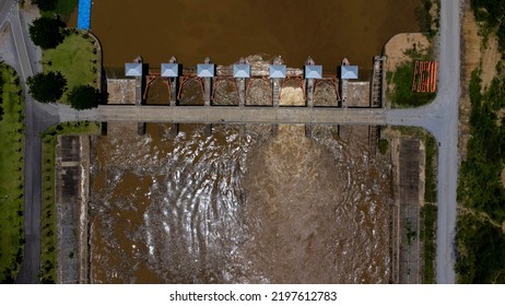 Aerial View Of Water Released From The Drainage Channel Of The Concrete Dam Is A Way Of Overflowing Water In The Rainy Season. Top View Of Turbid Brown Forest Water Flows From A Dam In Thailand.