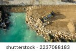 Aerial view of waterfront construction site with excavator. Bulldozer working on a breakwater construction