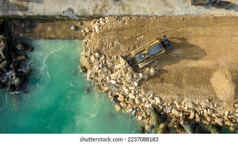 Aerial view of waterfront construction site with excavator. Bulldozer working on a breakwater construction - Shutterstock ID 2237088183