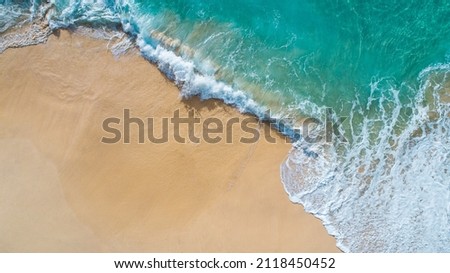 Aerial view waves break on white sand beach