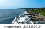 Aerial view of waves crashing over rocks near the Marginal Way running path in Ogunquit, Maine taken over the ocean.