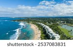 Aerial view of West Beach residences at Dorado Beach Resort, Puerto Rico, featuring luxury beachfront condos, a sandy beach with turquoise waters, lush greenery, and a golf course under blue skies. 