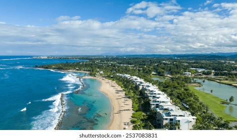 Aerial view of West Beach residences at Dorado Beach Resort, Puerto Rico, featuring luxury beachfront condos, a sandy beach with turquoise waters, lush greenery, and a golf course under blue skies.  - Powered by Shutterstock