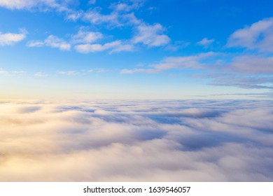 Aerial view White clouds in blue sky. Top view. View from drone. Aerial bird's eye. Aerial top cloudscape. Texture of clouds. View from above. Sunrise or sunset over clouds