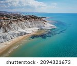Aerial view of white rocky cliffs at Scala dei Turchi, Sicily, Italy, with turquoise clear water. Drone shot of the limestone rock formation and beach. Tourist attraction, travel holiday scenery.