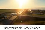 Aerial View of White Semi Truck with Cargo Trailer Passing Highway Overpass/ Bridge. Eighteen Wheeler is New, Loading Warehouses are Seen in the Background.