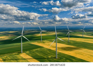 Aerial view of a wind farm with multiple turbines spinning in a vast green and yellow field under a cloudy blue sky.