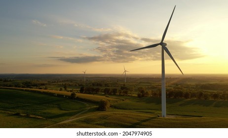 Aerial view of Wind turbines, windmill, farm, agricultural fields at sunrise sunset. Rural landscape. Renewable green energy concept, dawn dusk sky  - Powered by Shutterstock