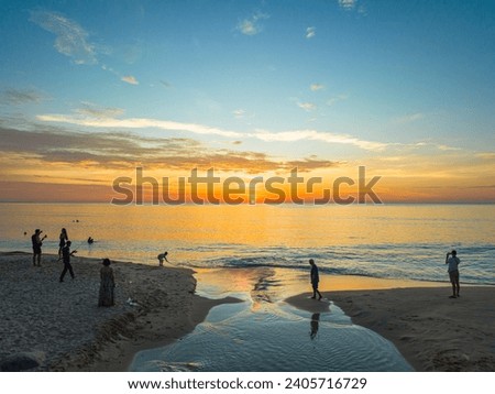 
aerial view of the winding canal on the sandy beach.
Tourists watch the sun set beside a small canal on a sandy beach.
beautiful sky reflection in the canal.
bubble waves and clear sand landscape.