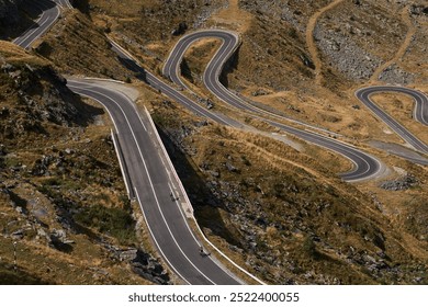 Aerial view of a winding mountain road with cyclists. Road is surrounded by dry grass and rocky terrain. Sportsmen training hard on bicycle outdoors.Sports motivation. Cycling professional group ride.