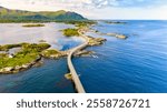 Aerial view of winding road over turquoise waters along Norway coastline, connecting small islands in a picturesque route through a stunning landscape. Atlantic Ocean Road Norway in summer