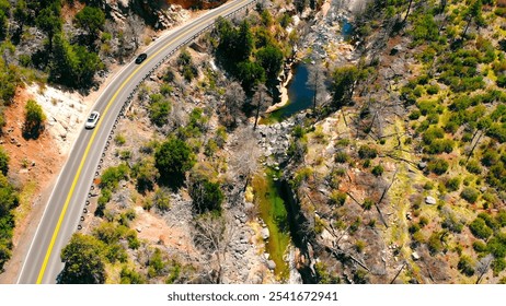 Aerial view of winding road through rocky canyon. A winding road curves along the edge of a rugged canyon with sparse vegetation. - Powered by Shutterstock