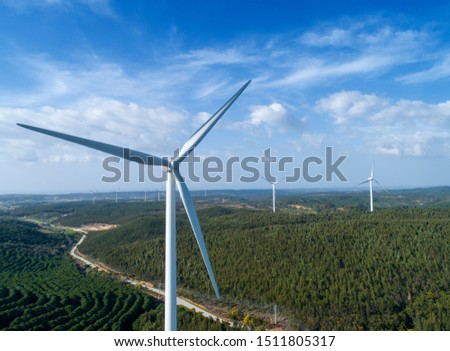 Aerial view of windmills or wind turbine on wind farm in rotation to generate electricity energy