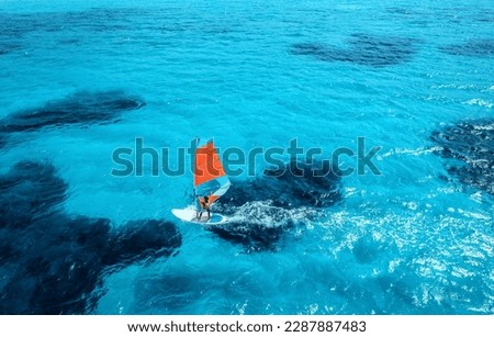 Aerial view of windsurfer on blue sea at sunny summer day. Windsurfing. Extreme sport and vacation. Top view of man on windsurfer board, waves, clear azure water in Sardinia, Italy. Tropical landscape Foto d'archivio © 