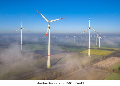 Aerial view of windturbines in the wind above mist layer on german countryside in the morning sun. Germany