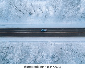 Aerial view of a winter road with snow covered forest 
