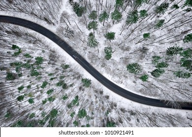 Aerial View Of Winter Road In Snowy Forest. Drone Captured Shot From Above.