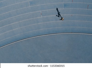 Aerial View Of A Woman Athlete Running On Athletic Track. Overhead View Of A Female Sprinter Running On Race Track In A Stadium.