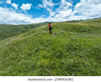 Aerial view of woman cyclist carrying a mountain bike climbing up to beautiful flowering grassland mountain top - Powered by Shutterstock