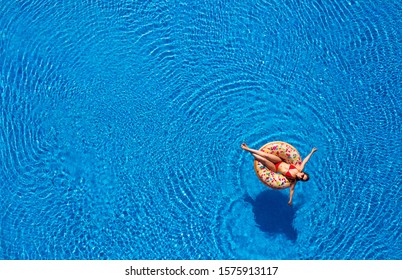Aerial view of a woman in red bikini lying on a donut in the pool. Concept of summer rest and relaxation - Shutterstock ID 1575913117