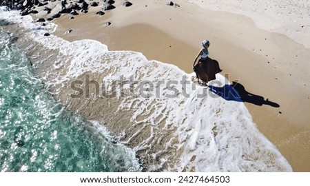 Aerial view of woman walking on the sandy beach with ocean waves braking on the coast. Summer vibes.