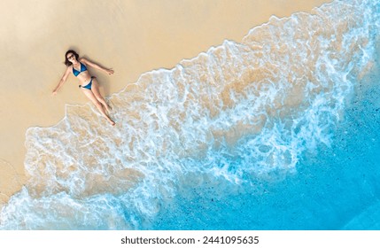 Aerial view of woman wearing blue bikini, she relaxes on the beach for summer vacation concept. Nature of the beach and sea Summer with sun, sand and sparkling seas. - Powered by Shutterstock