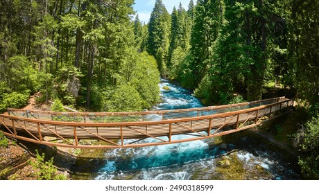 Aerial View of Wooden Bridge Over Rushing River in Dense Forest - Powered by Shutterstock