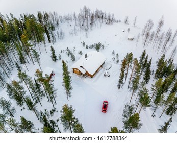 Aerial view of wooden log cabin or cottage in snow  winter forest by the lake in rural Finland Lapland